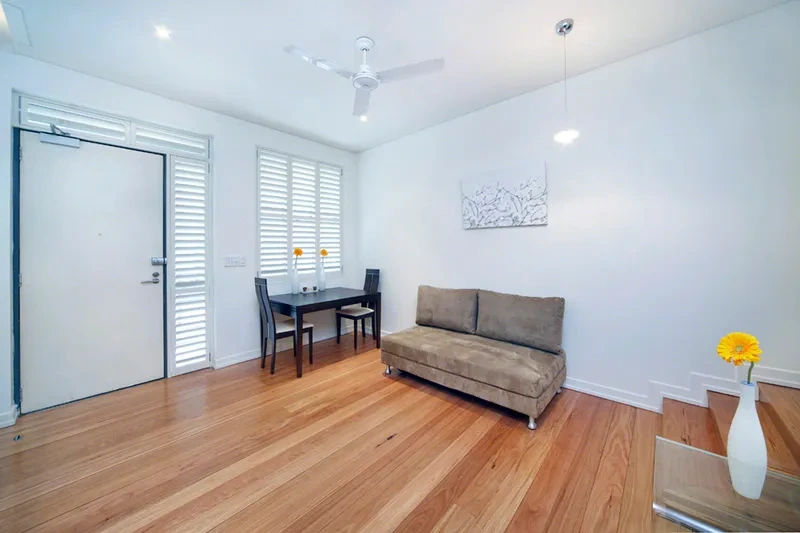 Furnished living and dining area with timber floors and plantation shutters in the Balmain studio
