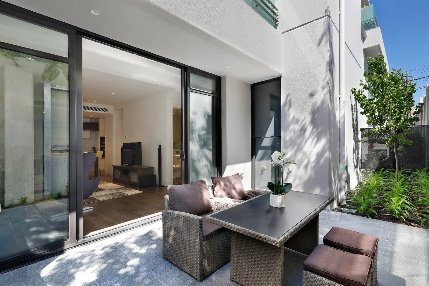 Living room opening to a leafy balcony at a Westprecinct serviced residence in Toorak